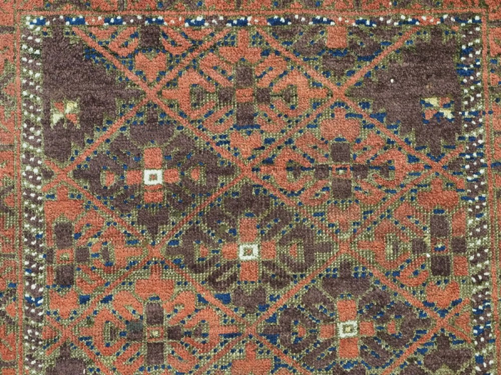 An antique hand-knotted Timuri Baluch rug featuring geometric diamond patterns in terracotta red, dark brown, and navy wool with fringed ends. View VIII
