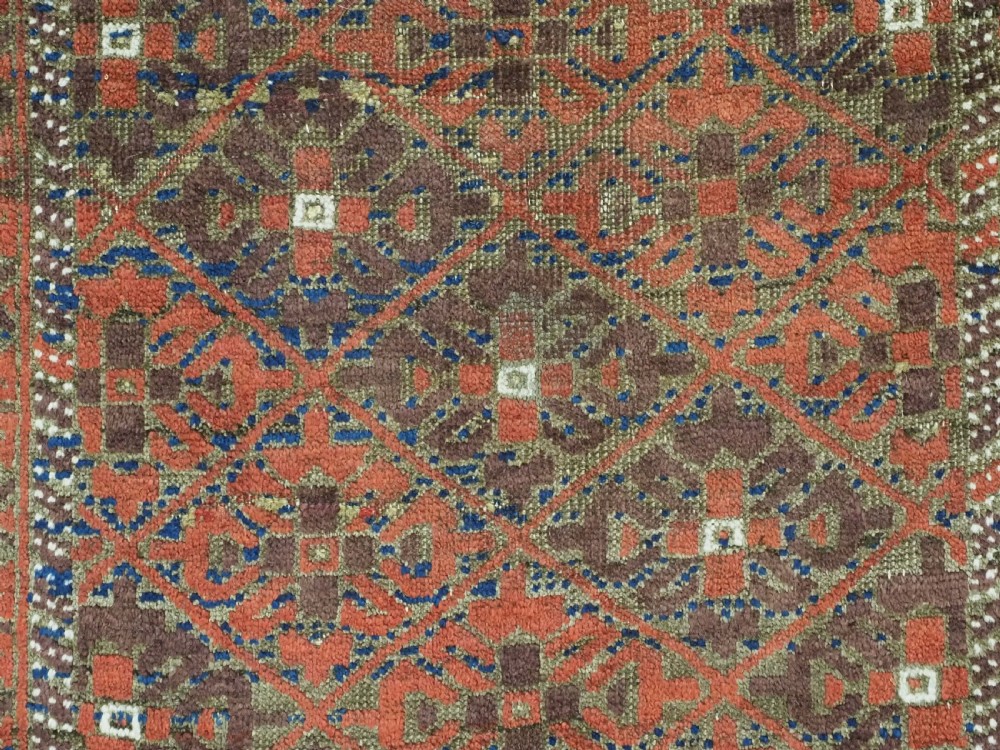 An antique hand-knotted Timuri Baluch rug featuring geometric diamond patterns in terracotta red, dark brown, and navy wool with fringed ends. View IX