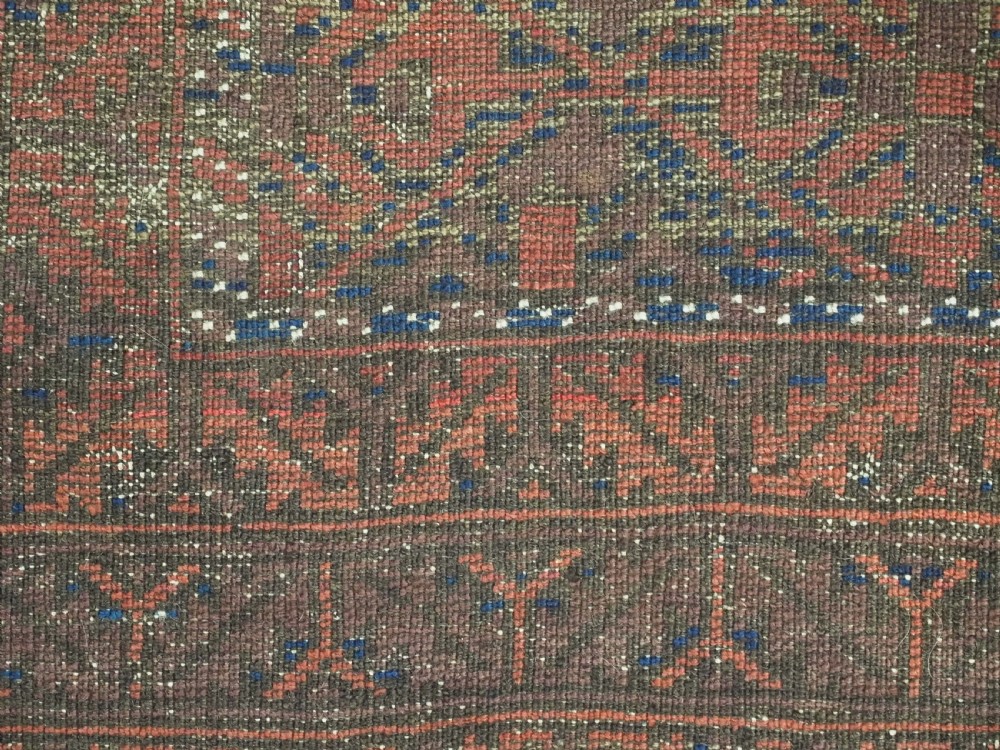 An antique hand-knotted Timuri Baluch rug featuring geometric diamond patterns in terracotta red, dark brown, and navy wool with fringed ends. View XII
