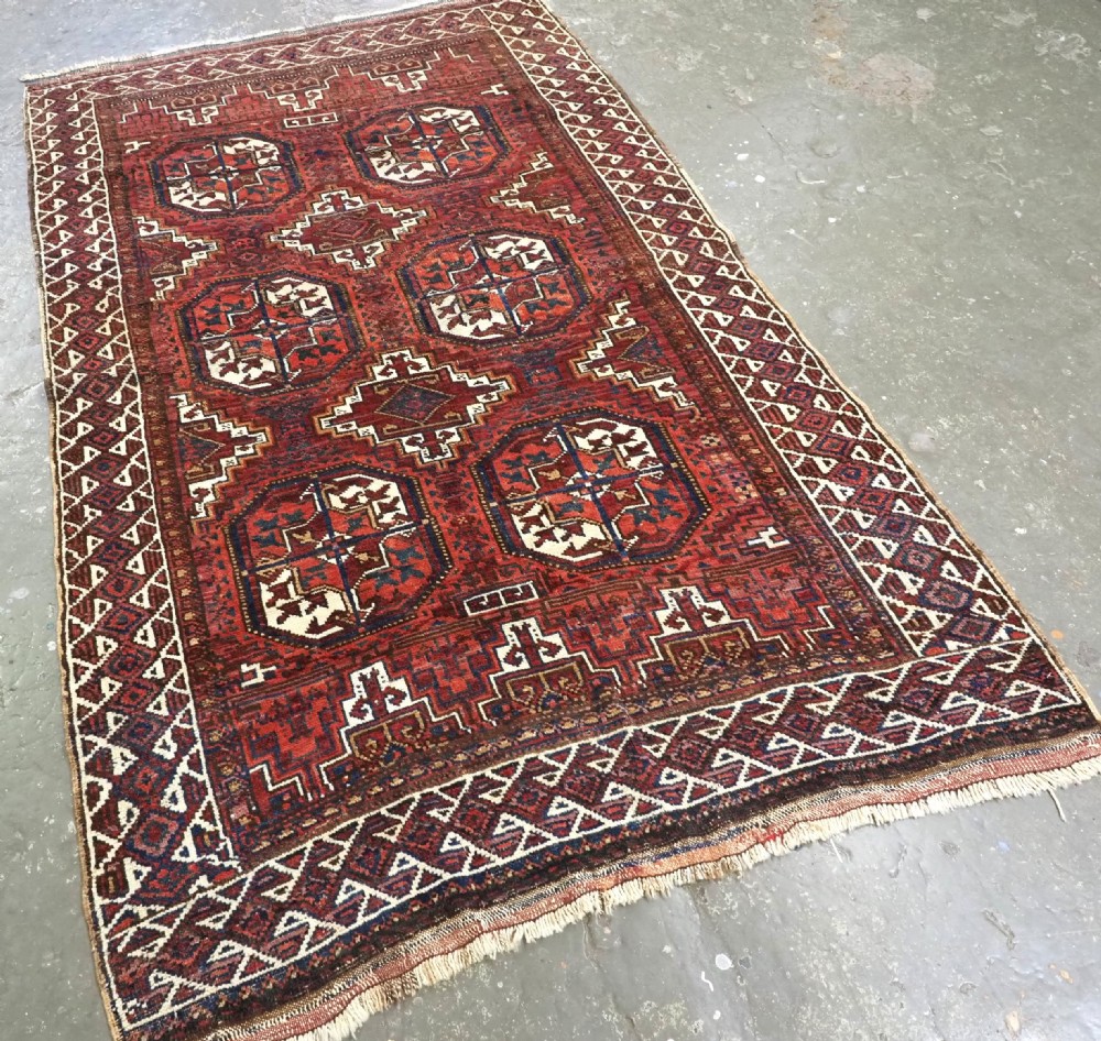 An antique hand-knotted wool rug featuring geometric octagonal medallions and diamond motifs in deep red, navy blue, and ivory tones. View II