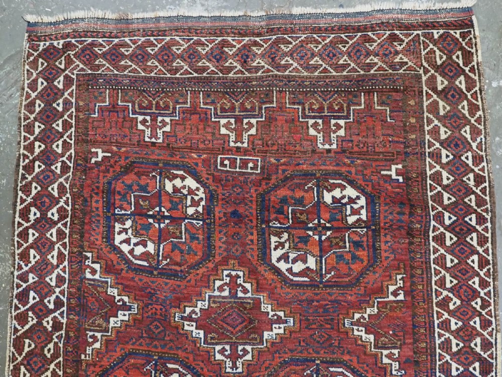 An antique hand-knotted wool rug featuring geometric octagonal medallions and diamond motifs in deep red, navy blue, and ivory tones. View III