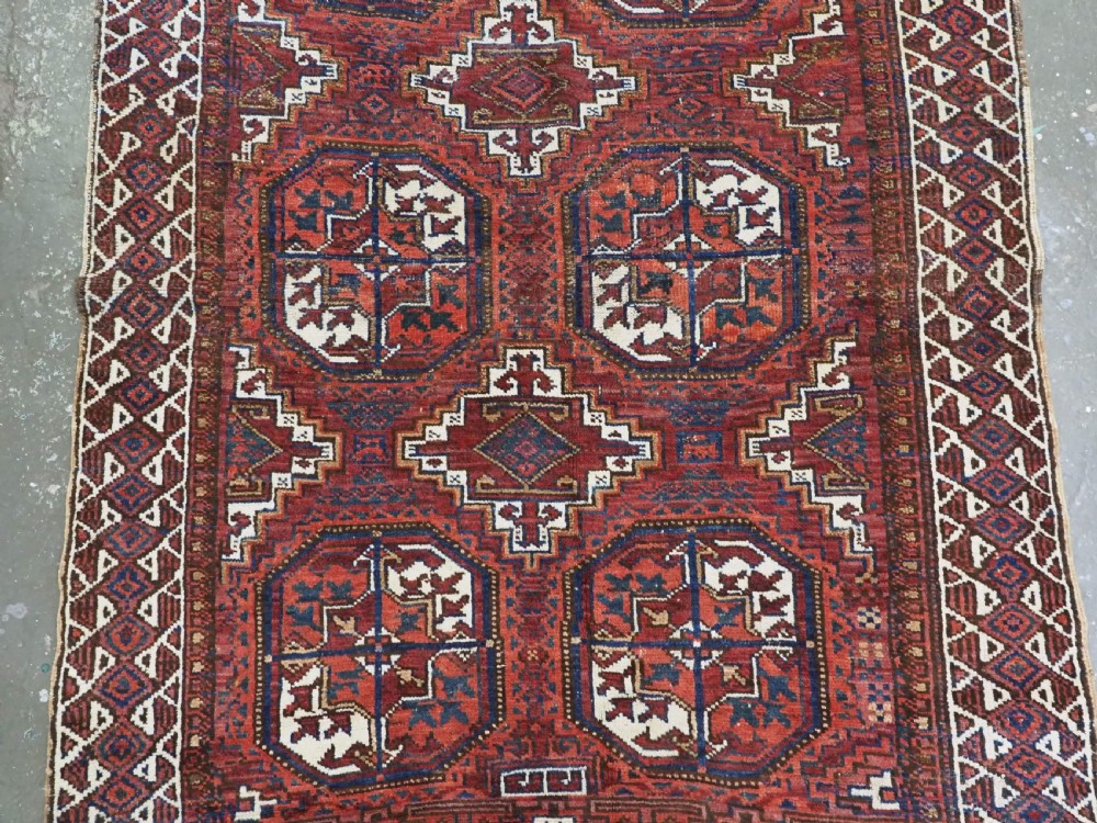 An antique hand-knotted wool rug featuring geometric octagonal medallions and diamond motifs in deep red, navy blue, and ivory tones. View IV