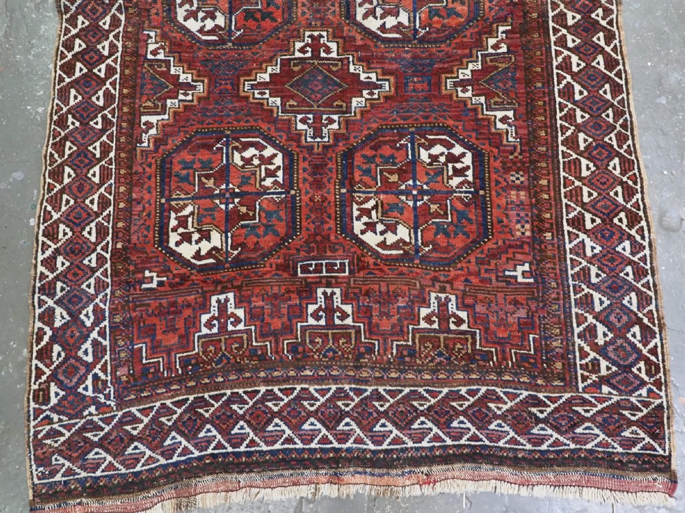 An antique hand-knotted wool rug featuring geometric octagonal medallions and diamond motifs in deep red, navy blue, and ivory tones. View V