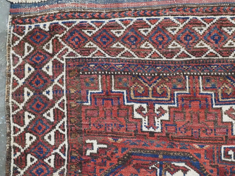 An antique hand-knotted wool rug featuring geometric octagonal medallions and diamond motifs in deep red, navy blue, and ivory tones. View VI