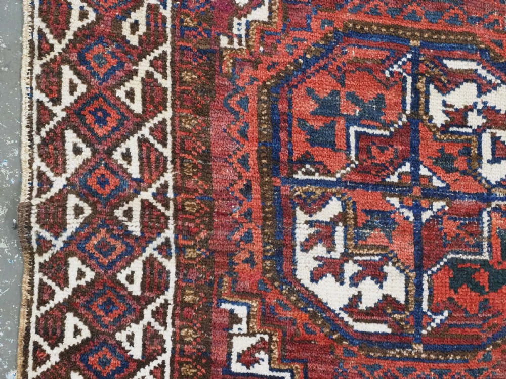 An antique hand-knotted wool rug featuring geometric octagonal medallions and diamond motifs in deep red, navy blue, and ivory tones. View VII