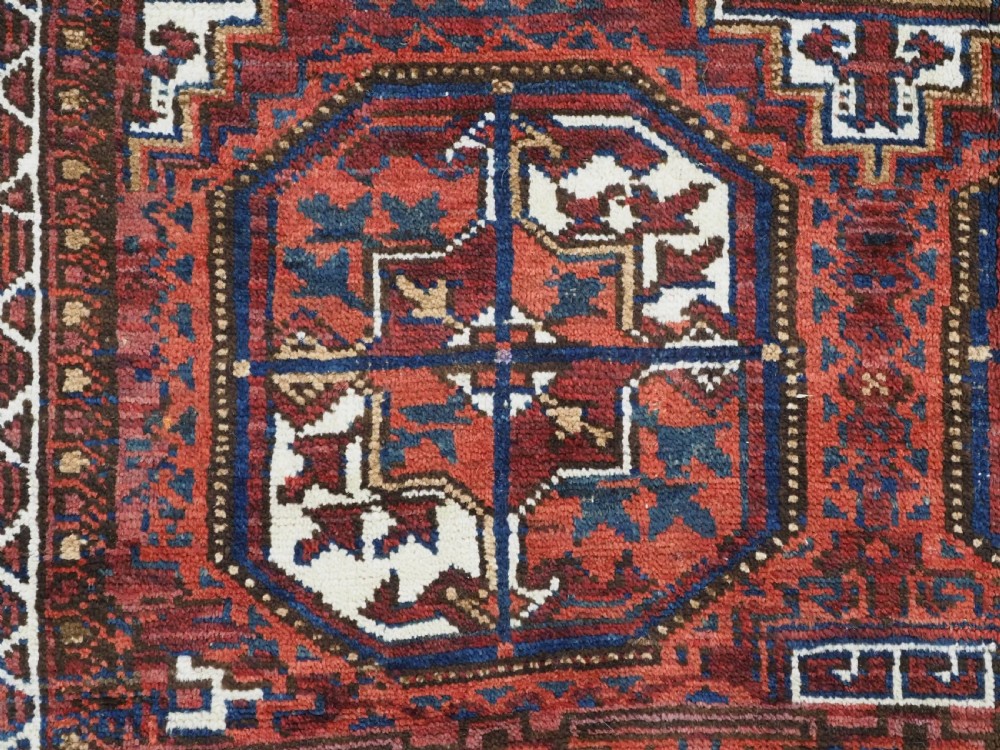 An antique hand-knotted wool rug featuring geometric octagonal medallions and diamond motifs in deep red, navy blue, and ivory tones. View X