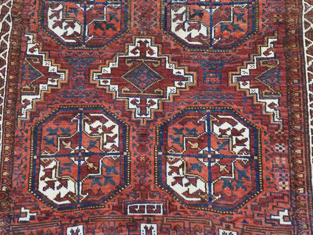 An antique hand-knotted wool rug featuring geometric octagonal medallions and diamond motifs in deep red, navy blue, and ivory tones. View XI