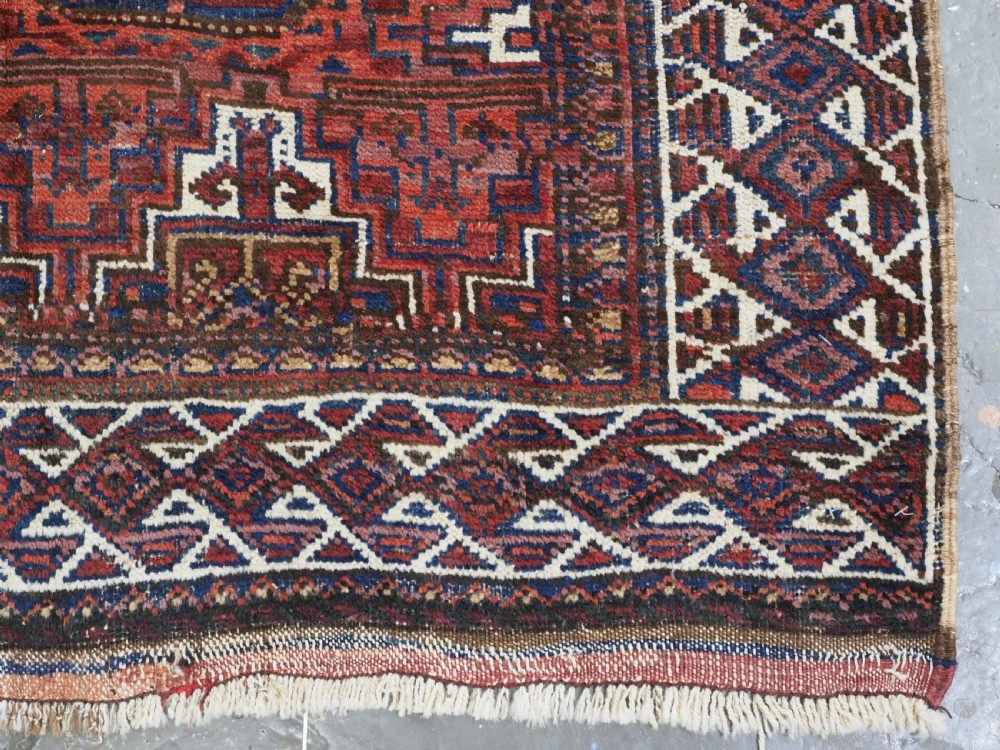 An antique hand-knotted wool rug featuring geometric octagonal medallions and diamond motifs in deep red, navy blue, and ivory tones. View XII