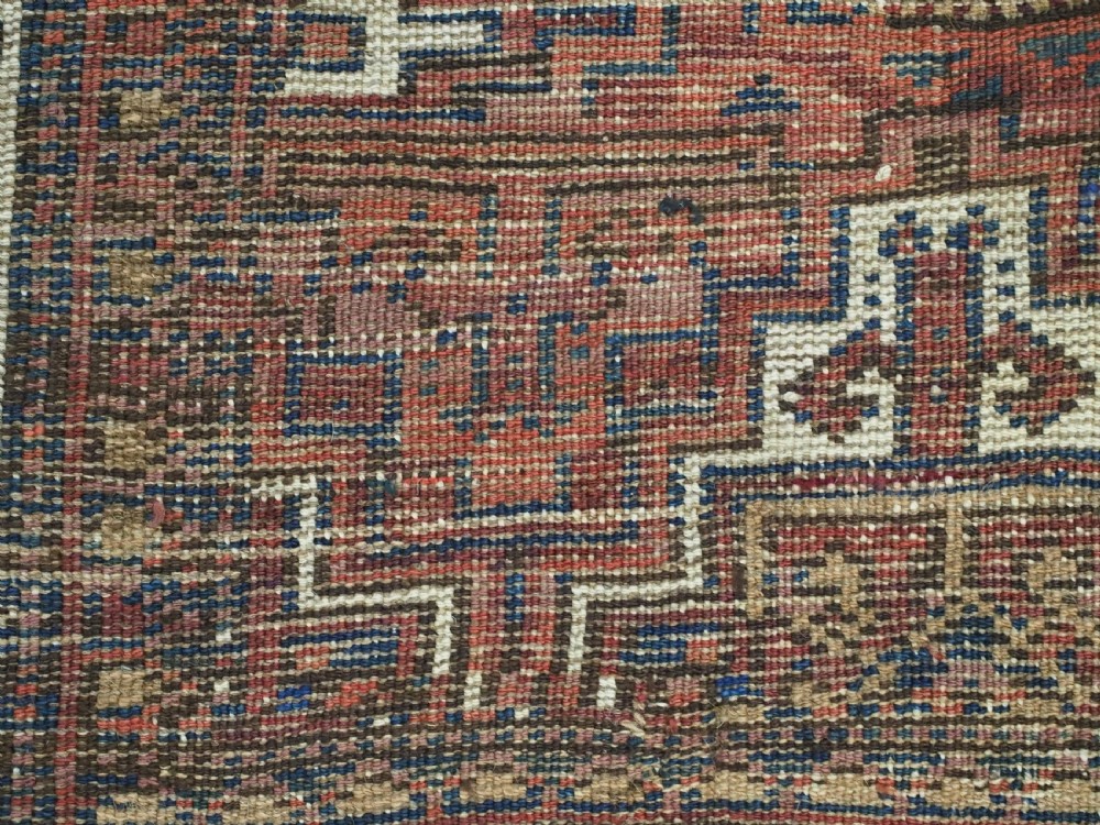 An antique hand-knotted wool rug featuring geometric octagonal medallions and diamond motifs in deep red, navy blue, and ivory tones. View XIII