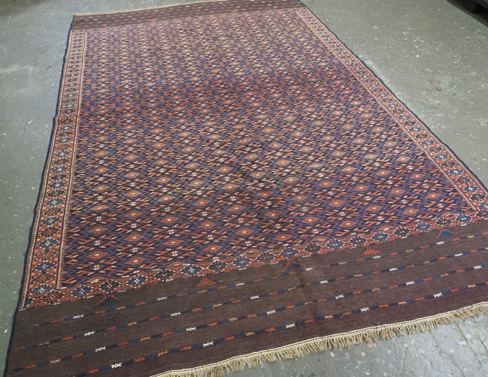 An antique Yomut Turkmen Soumak flatweave rug featuring an all-over geometric diamond lattice pattern in dark brown, terracotta, and navy blue. View II