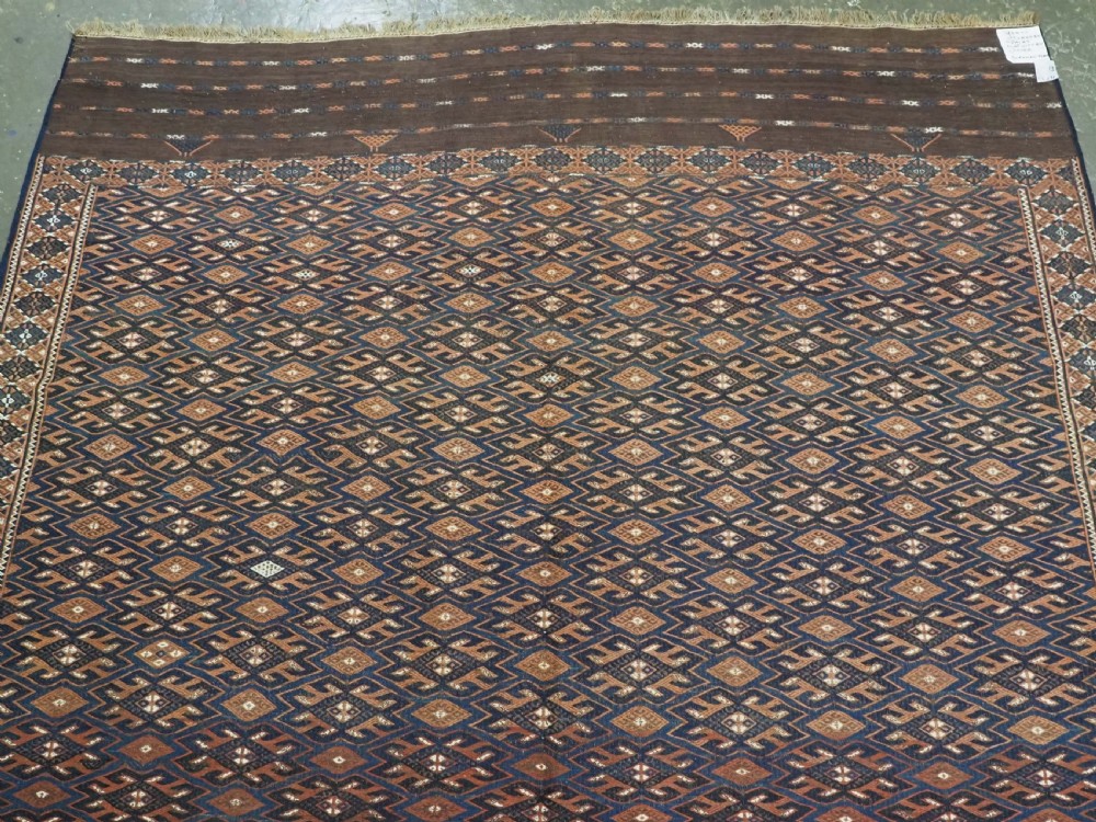 An antique Yomut Turkmen Soumak flatweave rug featuring an all-over geometric diamond lattice pattern in dark brown, terracotta, and navy blue. View III