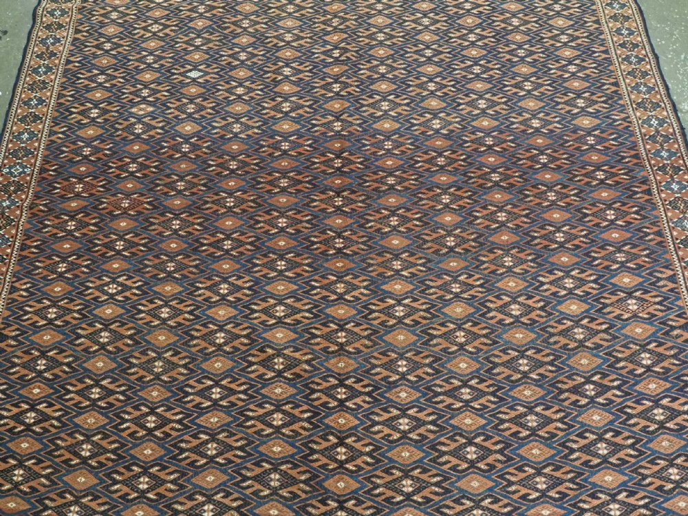 An antique Yomut Turkmen Soumak flatweave rug featuring an all-over geometric diamond lattice pattern in dark brown, terracotta, and navy blue. View IV
