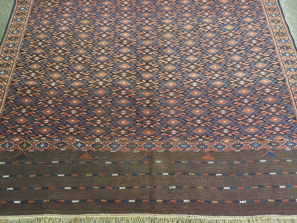 An antique Yomut Turkmen Soumak flatweave rug featuring an all-over geometric diamond lattice pattern in dark brown, terracotta, and navy blue. View V