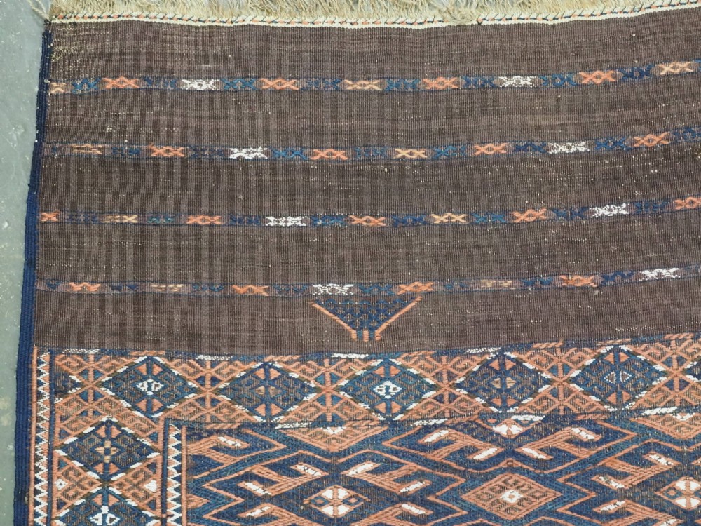 An antique Yomut Turkmen Soumak flatweave rug featuring an all-over geometric diamond lattice pattern in dark brown, terracotta, and navy blue. View VI