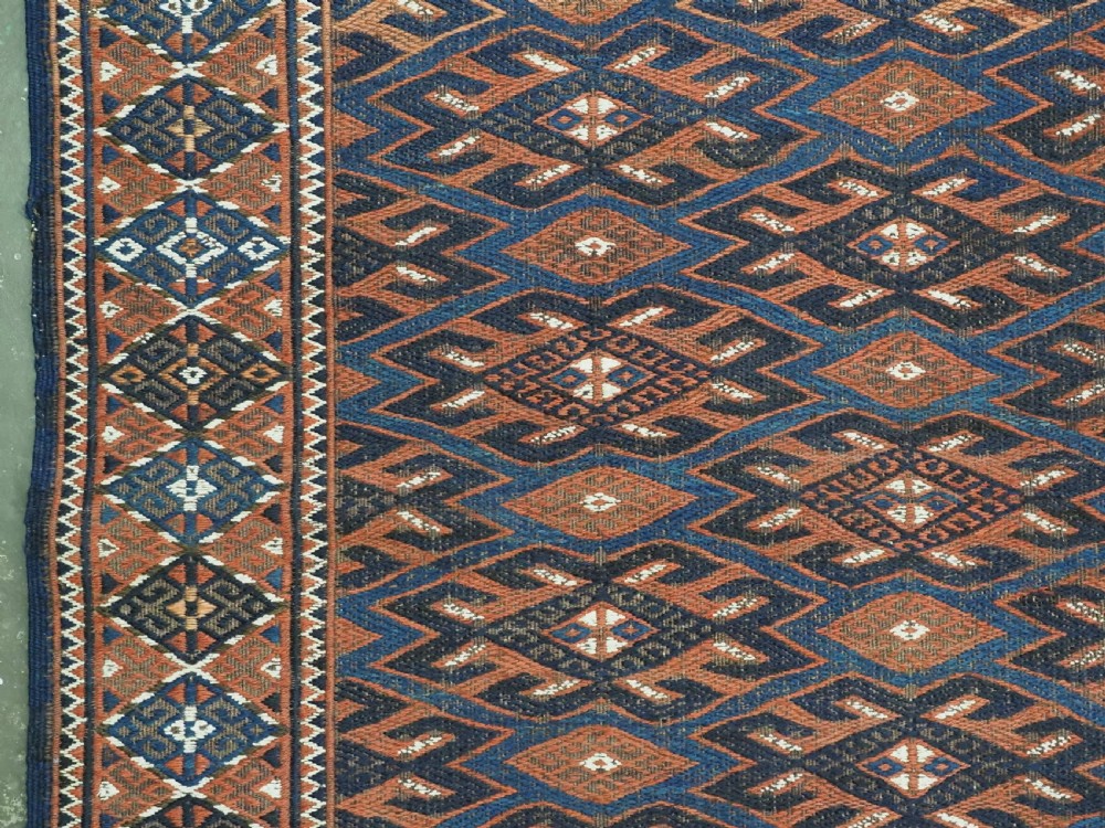 An antique Yomut Turkmen Soumak flatweave rug featuring an all-over geometric diamond lattice pattern in dark brown, terracotta, and navy blue. View VII