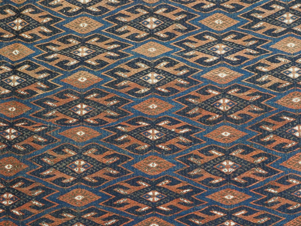 An antique Yomut Turkmen Soumak flatweave rug featuring an all-over geometric diamond lattice pattern in dark brown, terracotta, and navy blue. View X
