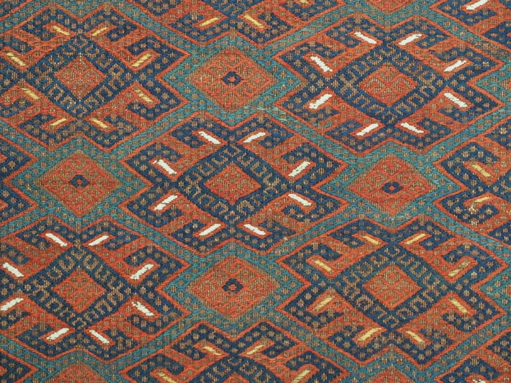 A rectangular handwoven wool kilim rug featuring a dense geometric diamond lattice pattern in terracotta red, navy blue, and cream with wide plain-woven border ends. View VIII