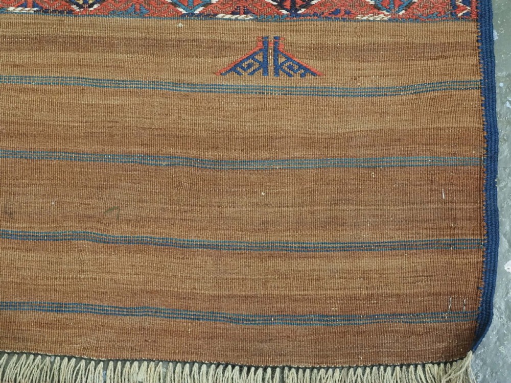 A rectangular handwoven wool kilim rug featuring a dense geometric diamond lattice pattern in terracotta red, navy blue, and cream with wide plain-woven border ends. View XIV