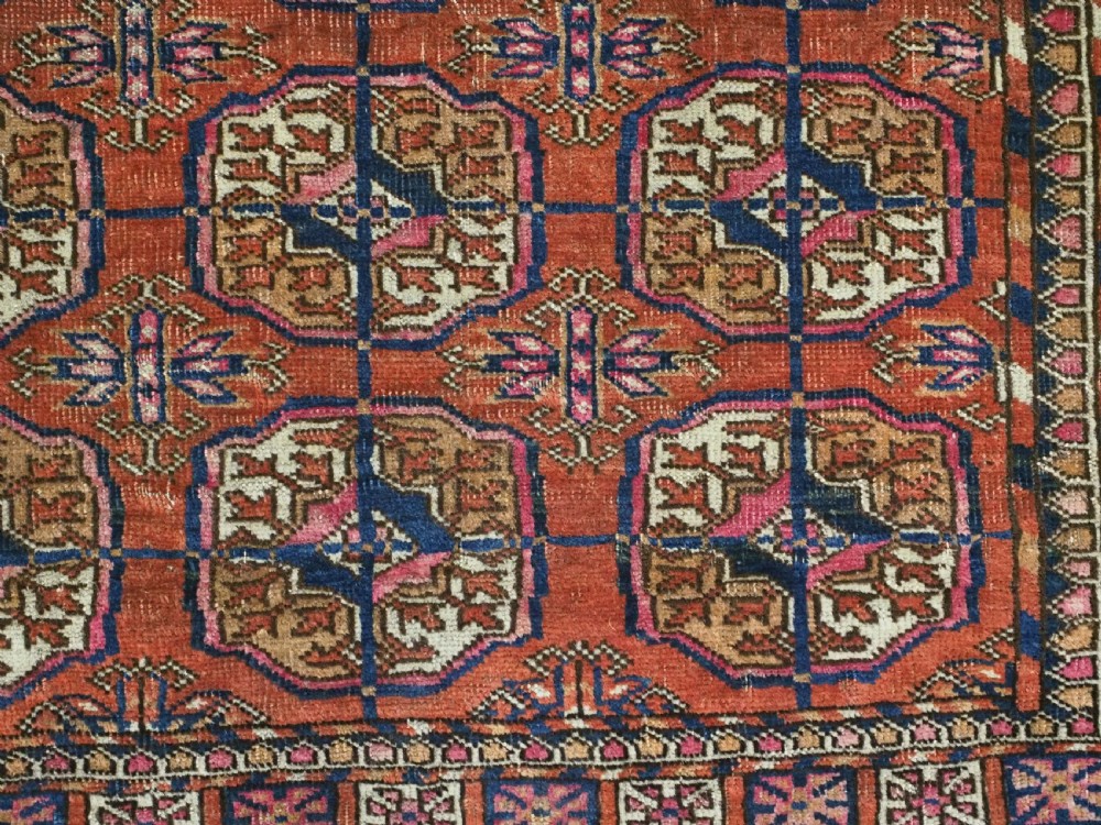 An antique Tekke Turkmen hand-knotted wool rug featuring repeating octagonal gul motifs on a deep brick red background with geometric borders. View VIII