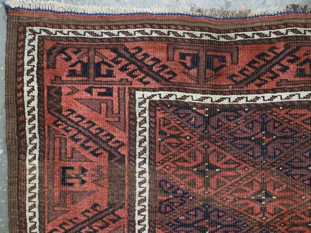 An antique 19th-century Khorasan Baluch wool rug featuring a repeating diamond calyx lattice pattern in rust red, dark navy, and brown with geometric borders. View VII