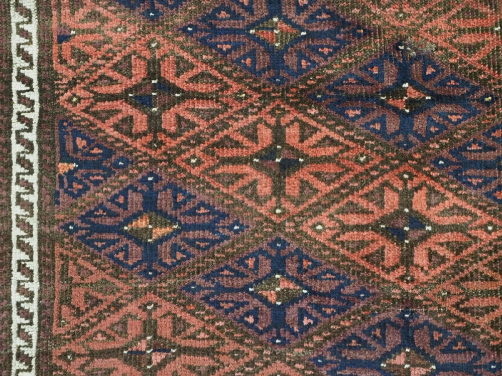 An antique 19th-century Khorasan Baluch wool rug featuring a repeating diamond calyx lattice pattern in rust red, dark navy, and brown with geometric borders. View XI