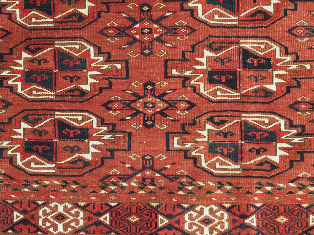 A rectangular hand-knotted red wool Turkmen chuval rug face featuring nine repeating octagonal gul motifs framed by geometric borders. View VI
