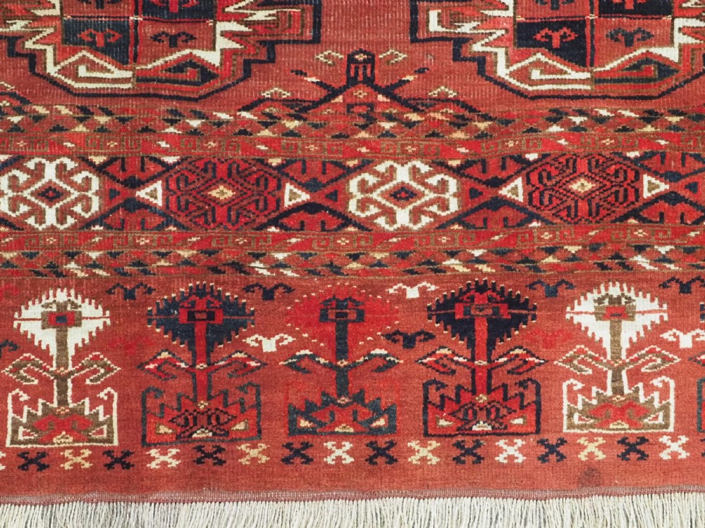 A rectangular hand-knotted red wool Turkmen chuval rug face featuring nine repeating octagonal gul motifs framed by geometric borders. View VIII