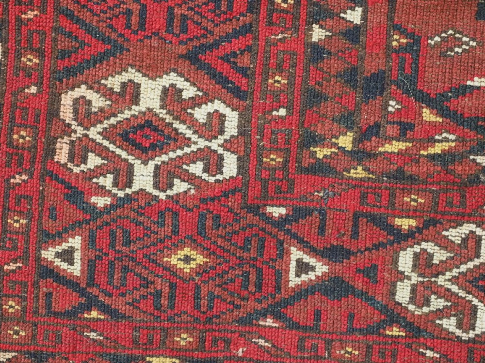 A rectangular hand-knotted red wool Turkmen chuval rug face featuring nine repeating octagonal gul motifs framed by geometric borders. View X