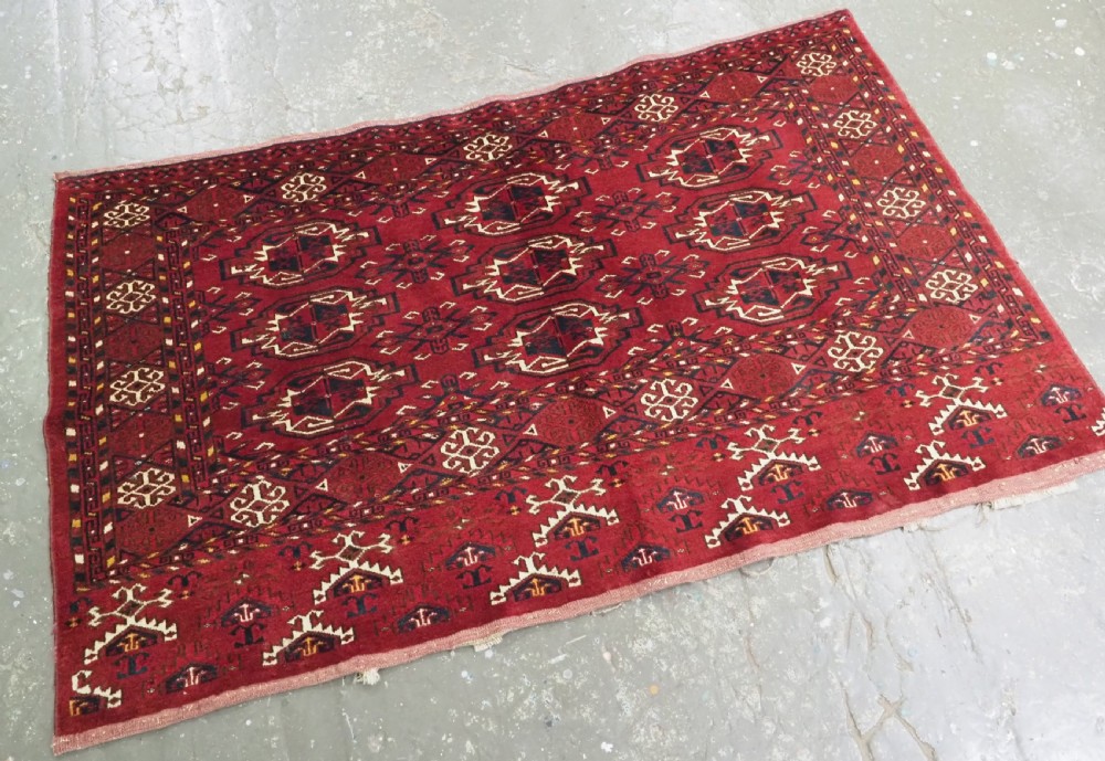 An antique hand-knotted Ersari Kizil Ayak Turkmen chuval face featuring nine octagonal guls on a deep red wool field with geometric borders. View II