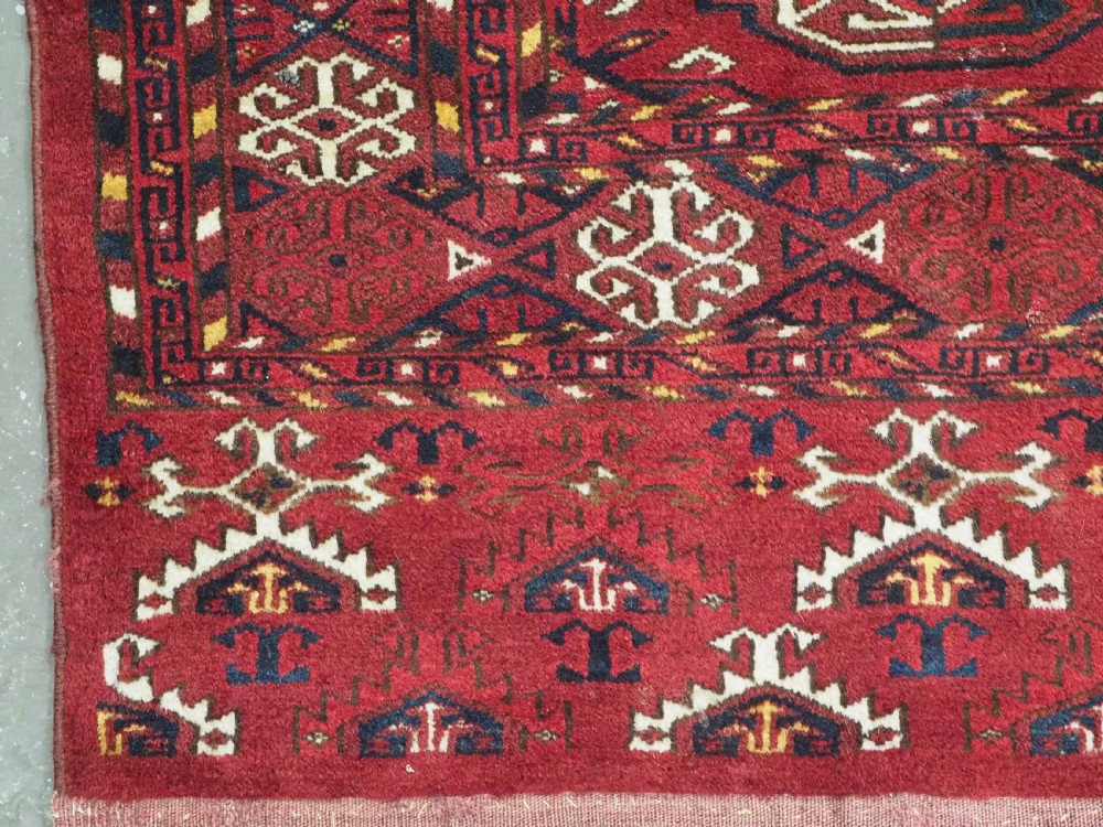 An antique hand-knotted Ersari Kizil Ayak Turkmen chuval face featuring nine octagonal guls on a deep red wool field with geometric borders. View V
