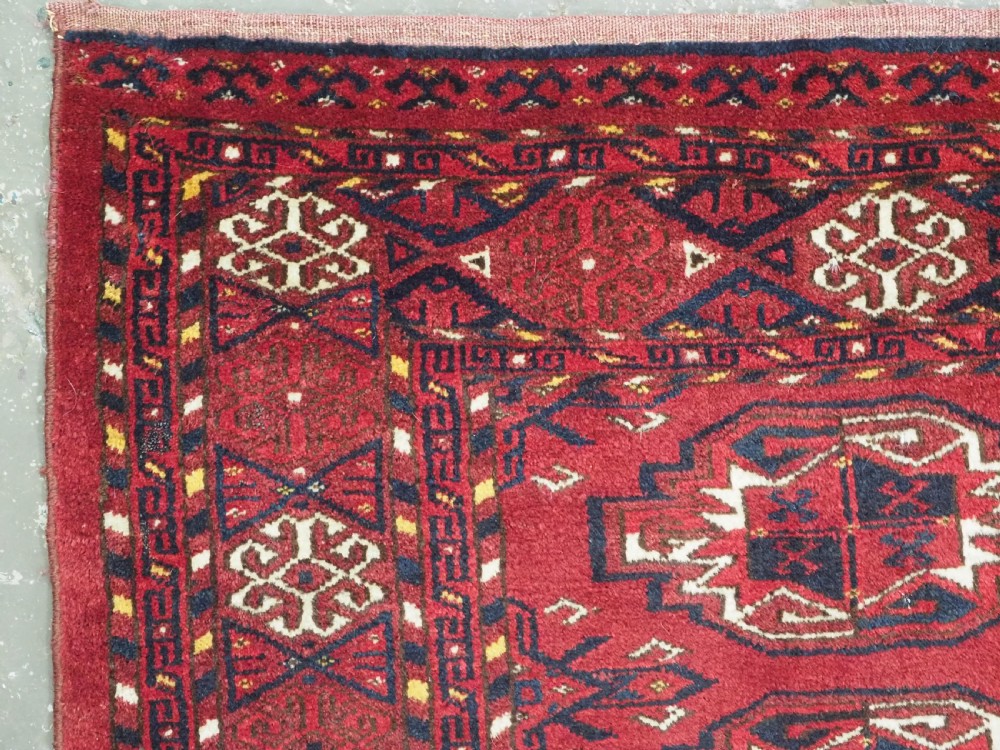 An antique hand-knotted Ersari Kizil Ayak Turkmen chuval face featuring nine octagonal guls on a deep red wool field with geometric borders. View VI