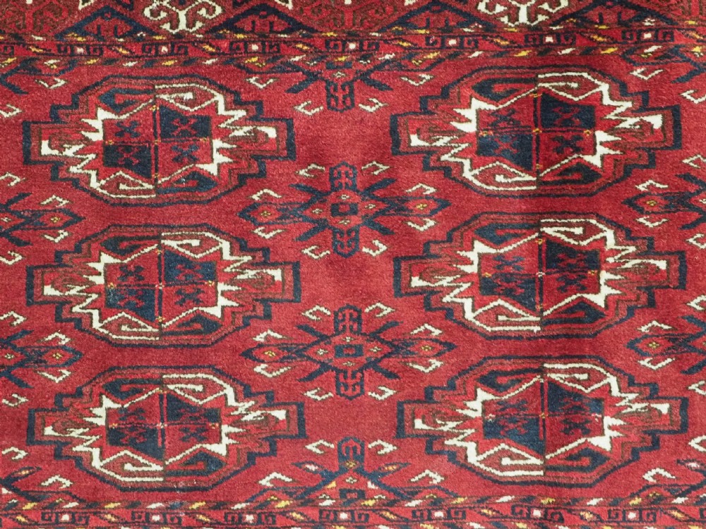 An antique hand-knotted Ersari Kizil Ayak Turkmen chuval face featuring nine octagonal guls on a deep red wool field with geometric borders. View VII