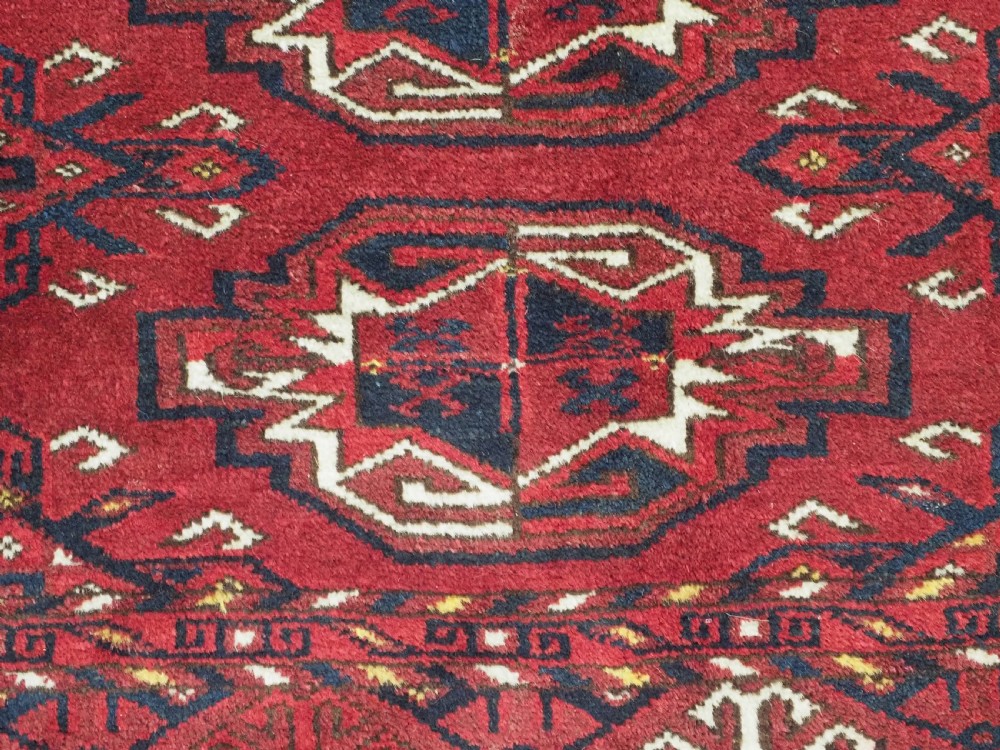 An antique hand-knotted Ersari Kizil Ayak Turkmen chuval face featuring nine octagonal guls on a deep red wool field with geometric borders. View VIII