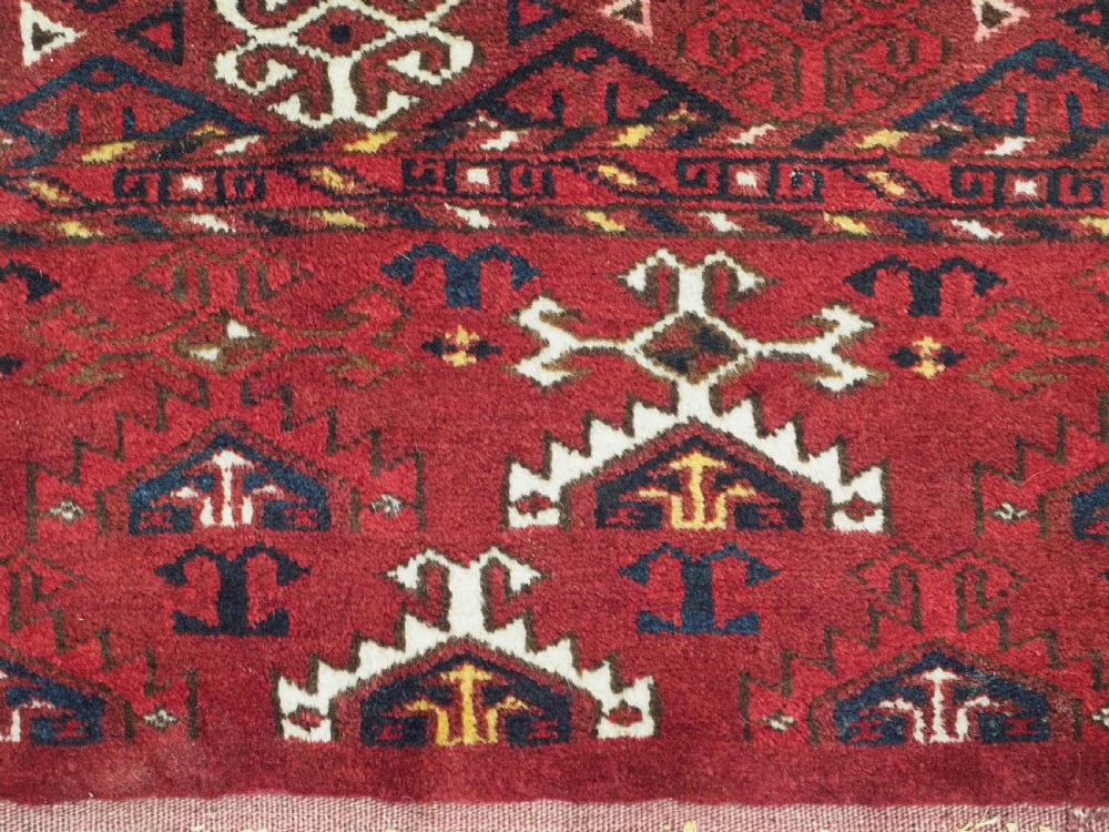 An antique hand-knotted Ersari Kizil Ayak Turkmen chuval face featuring nine octagonal guls on a deep red wool field with geometric borders. View IX