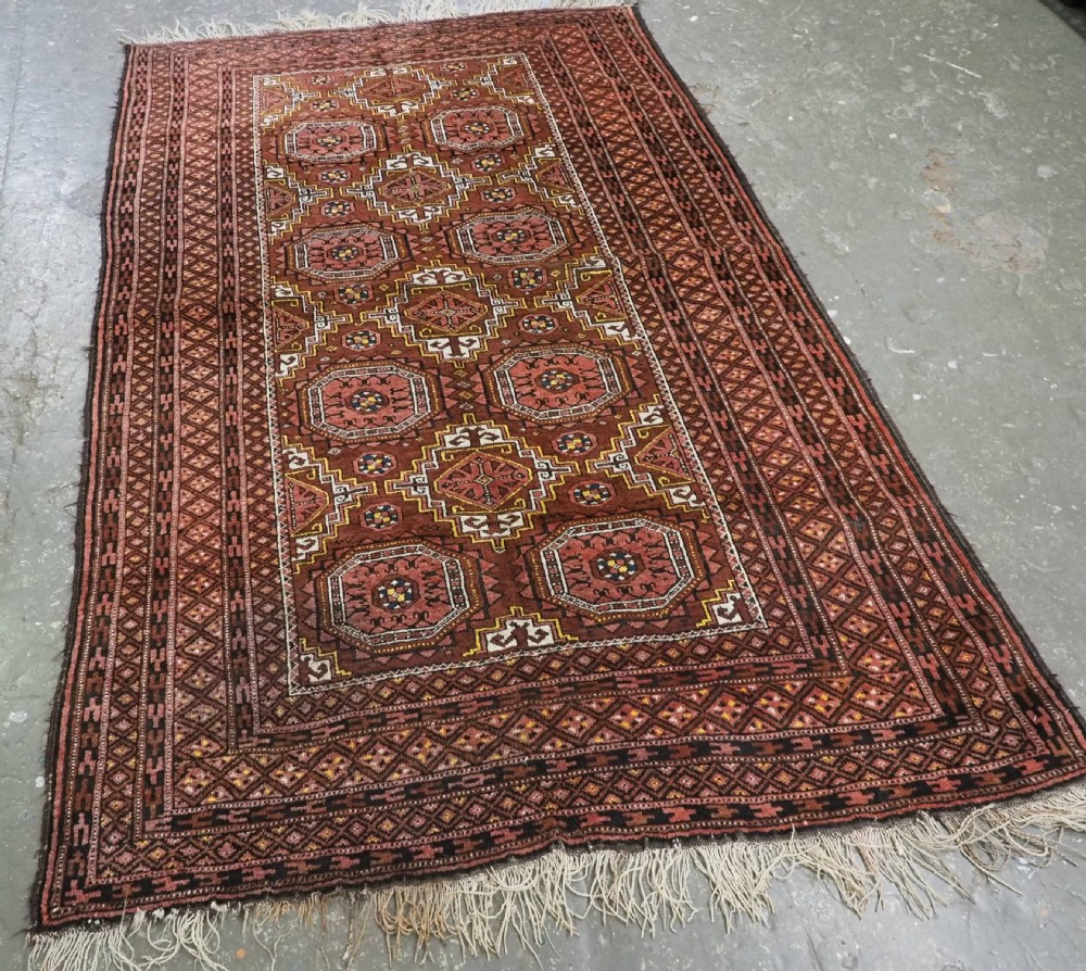 An antique hand-woven Salar Khani Baluch wool rug featuring geometric octagonal gul motifs in rust red, terracotta, and dark brown tones. View II