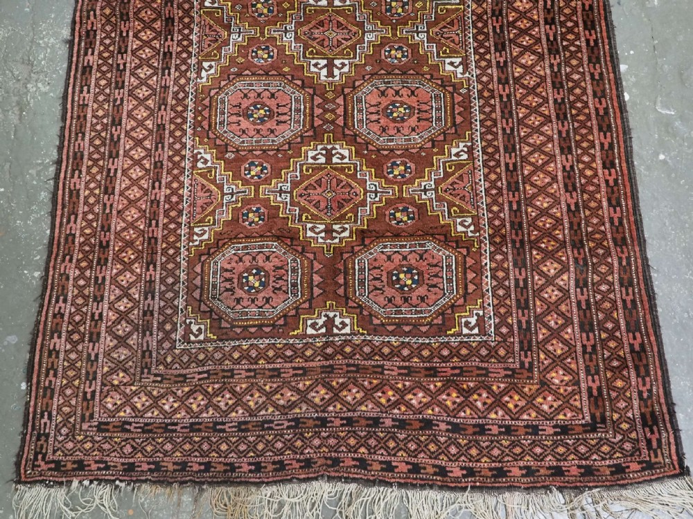 An antique hand-woven Salar Khani Baluch wool rug featuring geometric octagonal gul motifs in rust red, terracotta, and dark brown tones. View VI