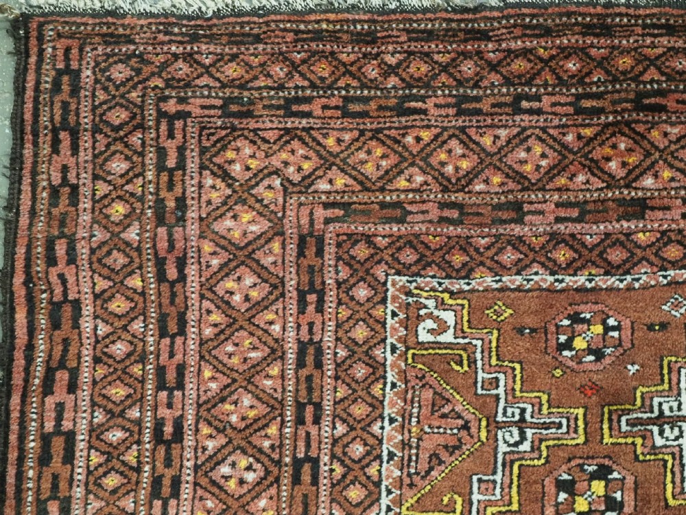 An antique hand-woven Salar Khani Baluch wool rug featuring geometric octagonal gul motifs in rust red, terracotta, and dark brown tones. View VII