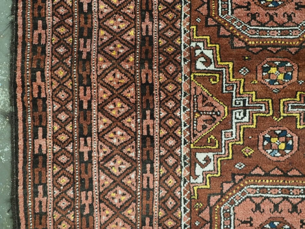An antique hand-woven Salar Khani Baluch wool rug featuring geometric octagonal gul motifs in rust red, terracotta, and dark brown tones. View VIII