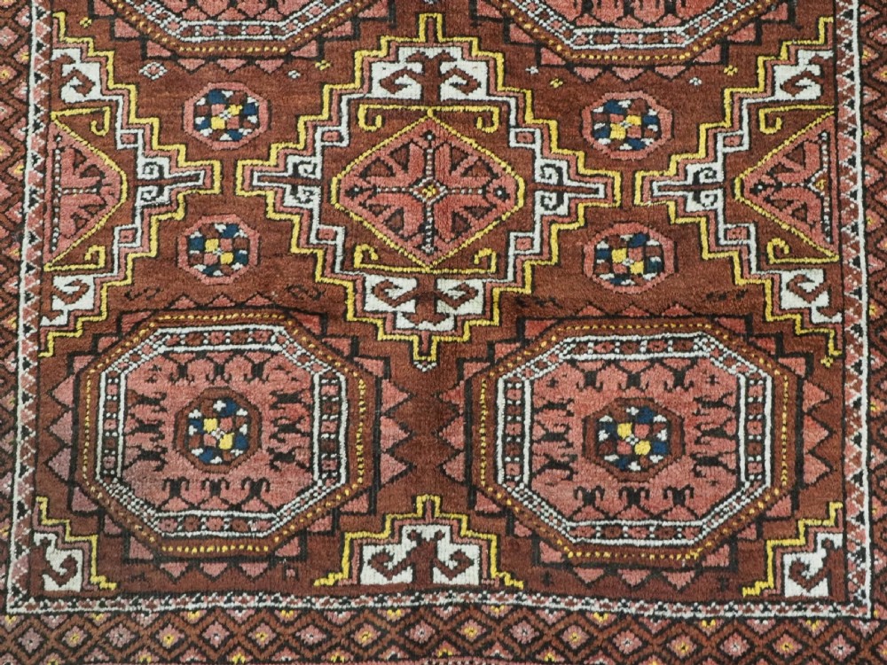 An antique hand-woven Salar Khani Baluch wool rug featuring geometric octagonal gul motifs in rust red, terracotta, and dark brown tones. View XI