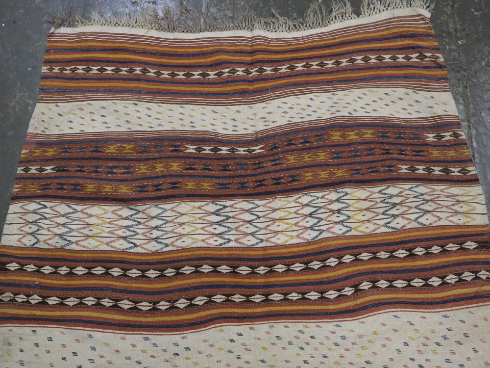 A flatwoven wool kilim rug featuring horizontal bands of cream, dark brown, and ochre with geometric diamond patterns. View III