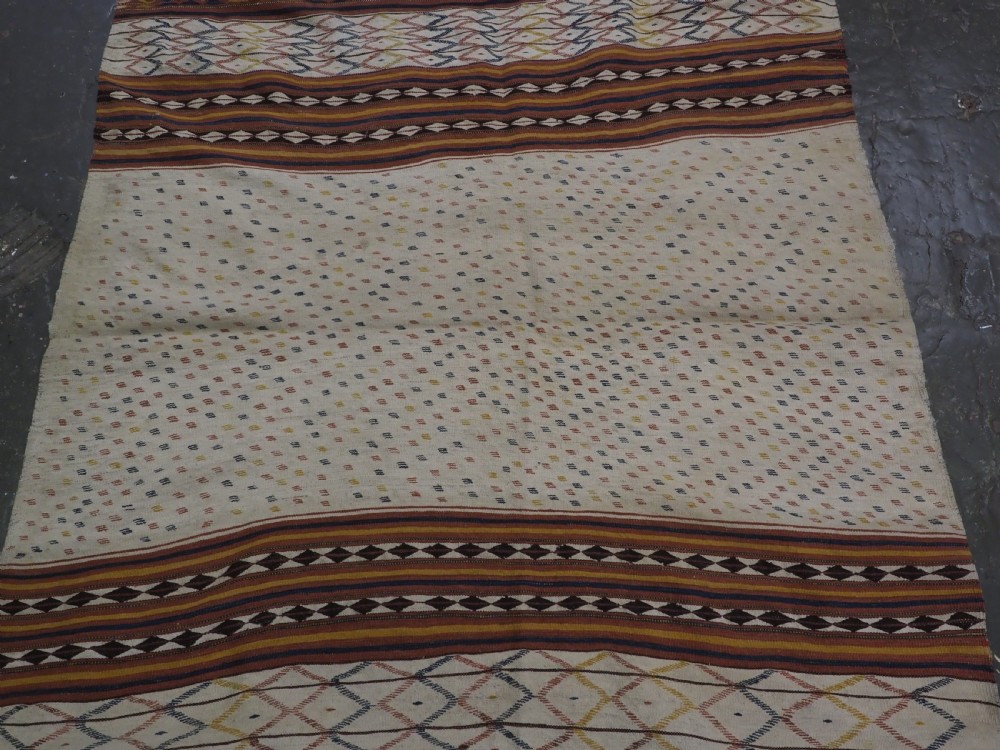 A flatwoven wool kilim rug featuring horizontal bands of cream, dark brown, and ochre with geometric diamond patterns. View IV