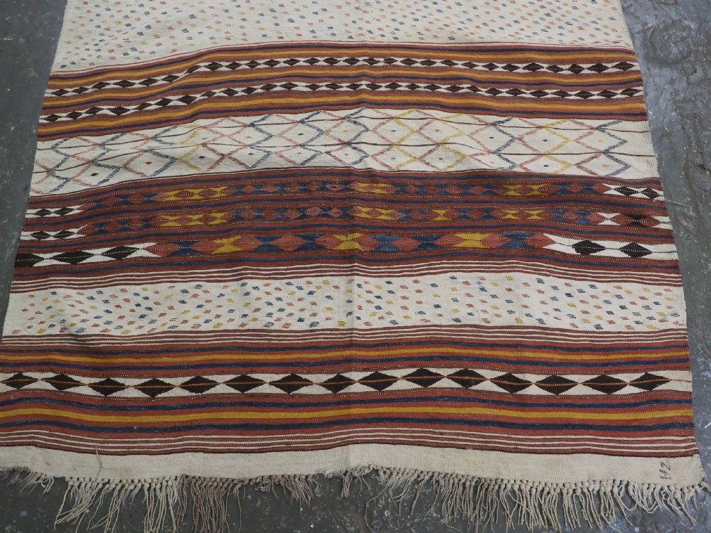 A flatwoven wool kilim rug featuring horizontal bands of cream, dark brown, and ochre with geometric diamond patterns. View V