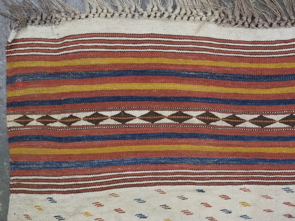 A flatwoven wool kilim rug featuring horizontal bands of cream, dark brown, and ochre with geometric diamond patterns. View VI