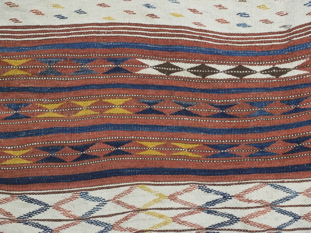 A flatwoven wool kilim rug featuring horizontal bands of cream, dark brown, and ochre with geometric diamond patterns. View VII