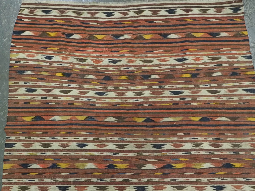 A long handwoven flatweave wool runner rug featuring horizontal bands of terracotta, dark brown, yellow, and cream geometric patterns. View III