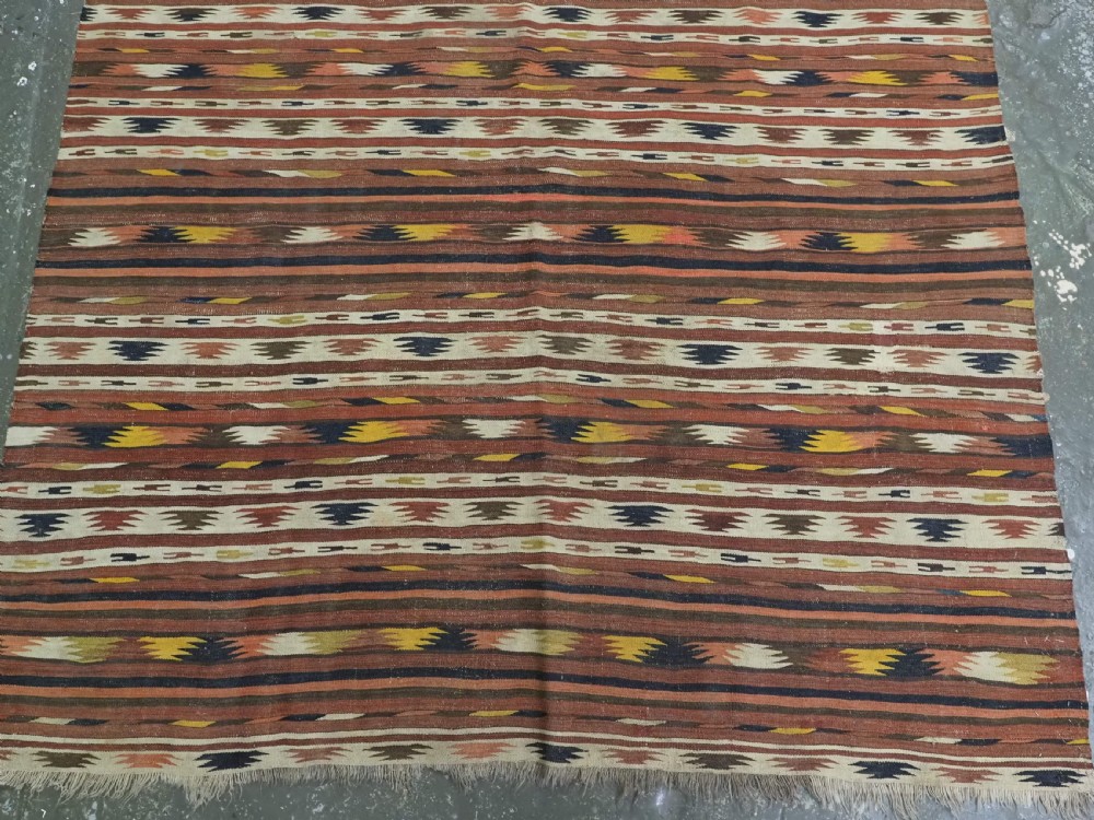A long handwoven flatweave wool runner rug featuring horizontal bands of terracotta, dark brown, yellow, and cream geometric patterns. View VI