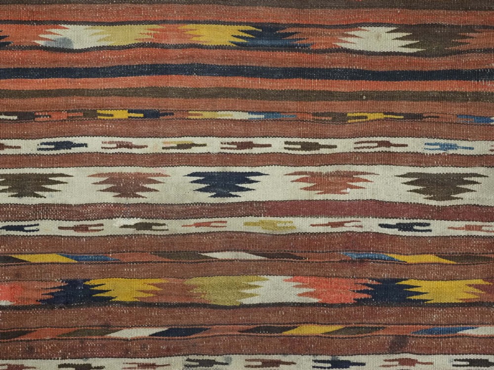 A long handwoven flatweave wool runner rug featuring horizontal bands of terracotta, dark brown, yellow, and cream geometric patterns. View VIII