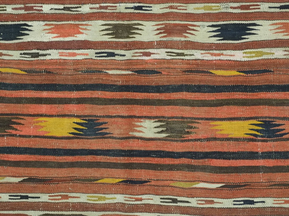 A long handwoven flatweave wool runner rug featuring horizontal bands of terracotta, dark brown, yellow, and cream geometric patterns. View X
