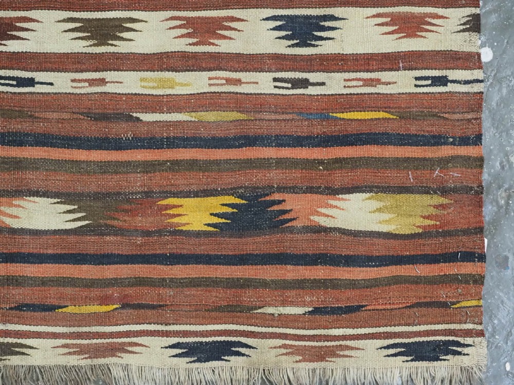 A long handwoven flatweave wool runner rug featuring horizontal bands of terracotta, dark brown, yellow, and cream geometric patterns. View XII