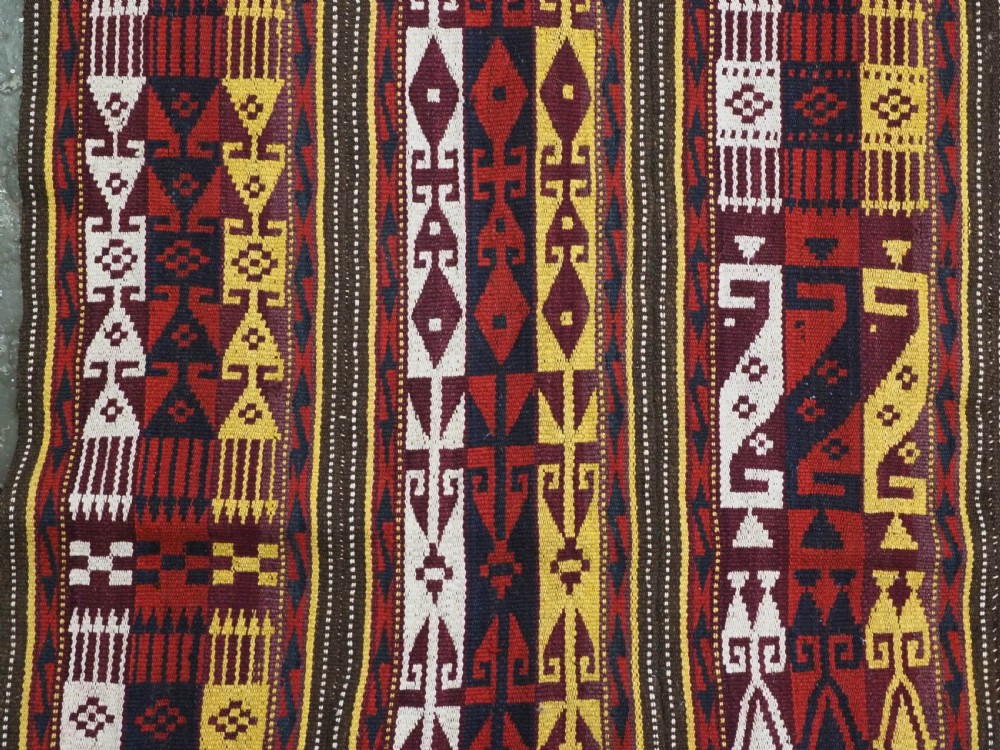 An antique handwoven Uzbek Gajeri wool kilim rug featuring vertical bands of geometric motifs in red, yellow, black, and cream shades. View VI
